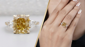 A close-up and on-hand view of a three-stone engagement ring featuring a prominent fancy yellow cushion-cut diamond flanked by two colorless step-cut side diamonds on a gold band.